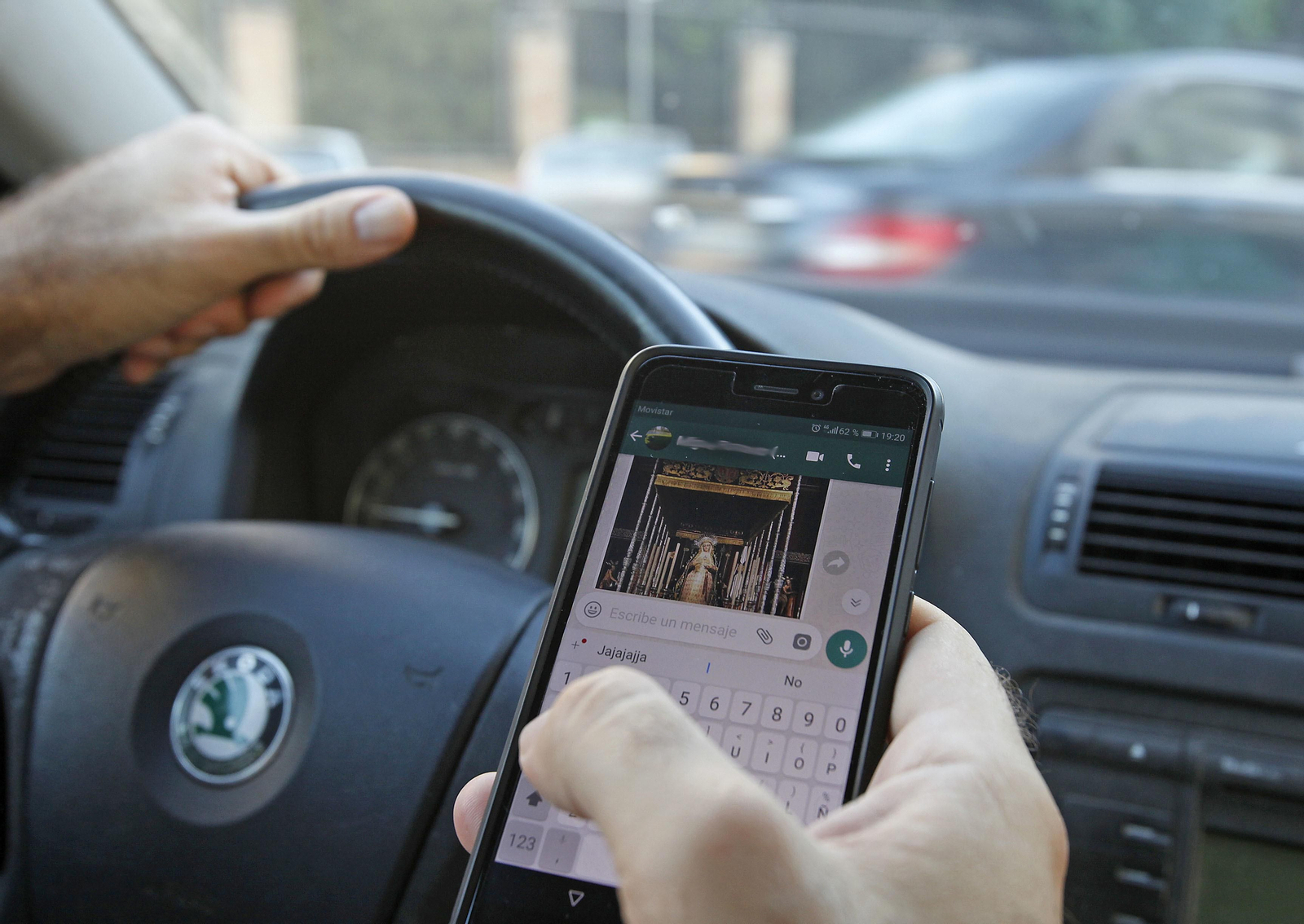Un conductor consulta el whatsapp mientras conduce