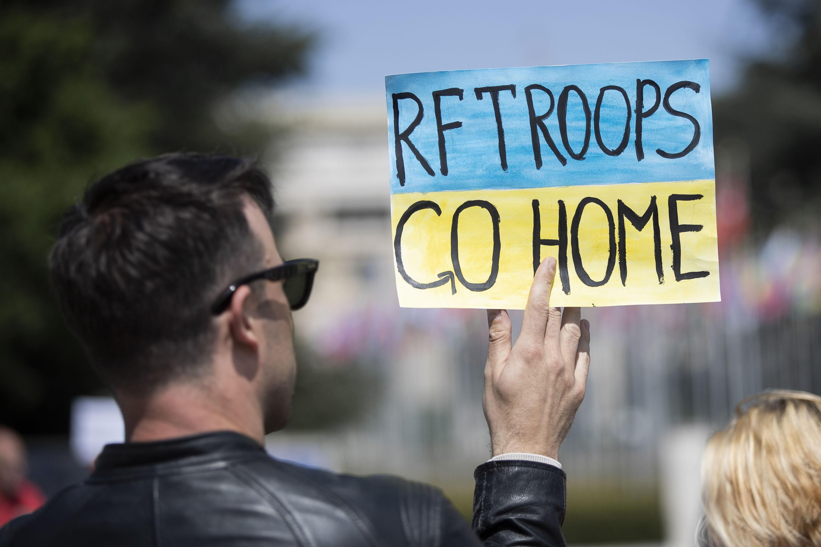 Un hombre muestra un cartel contra la invasión durante una protesta en Ginebra.
