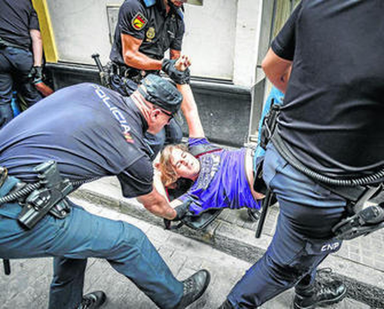 Uno de los activistas contra el desahucio es sacado de la vivienda por los agentes.