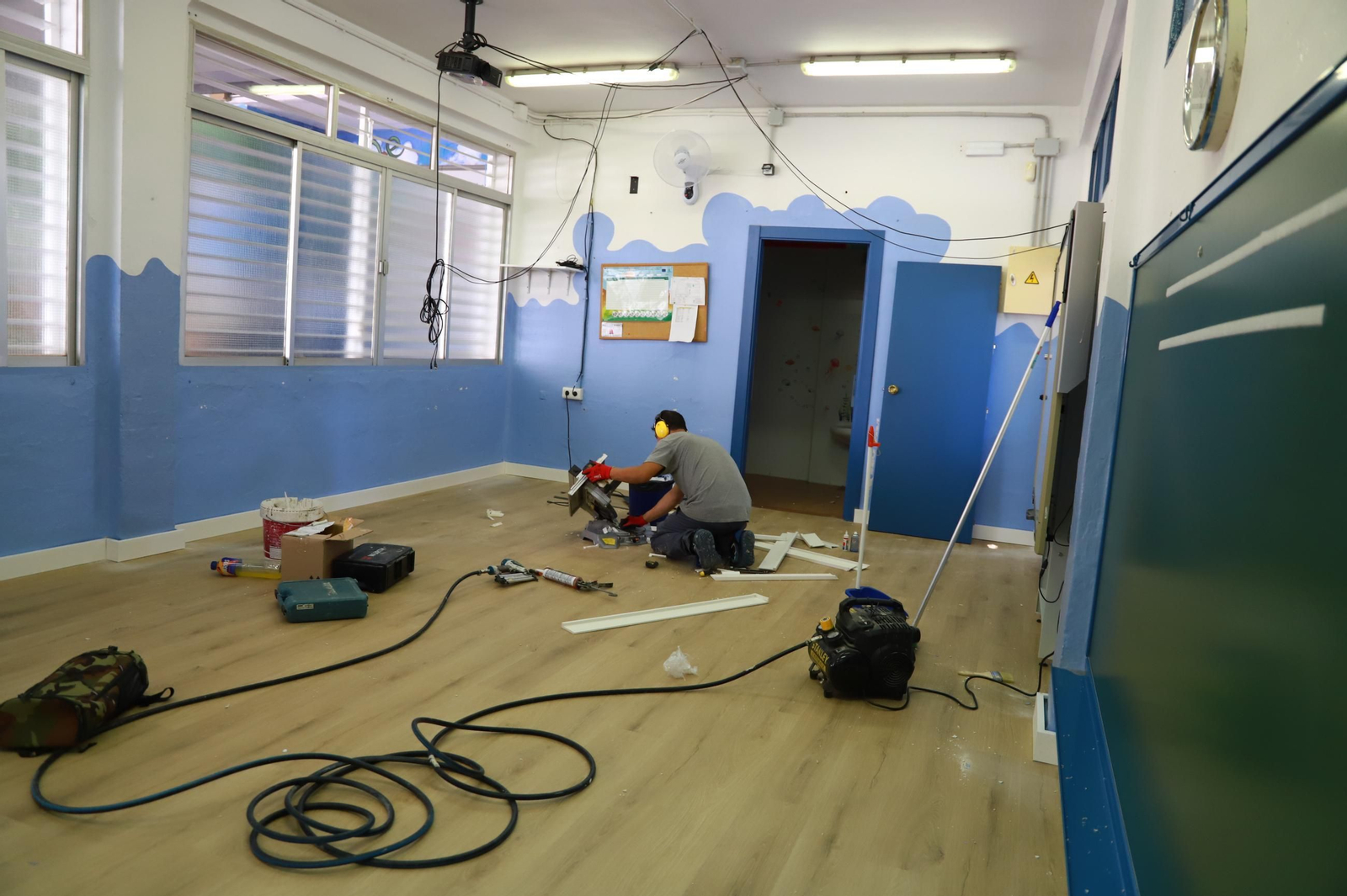 Un operario realizando labores de mejora en un aula.