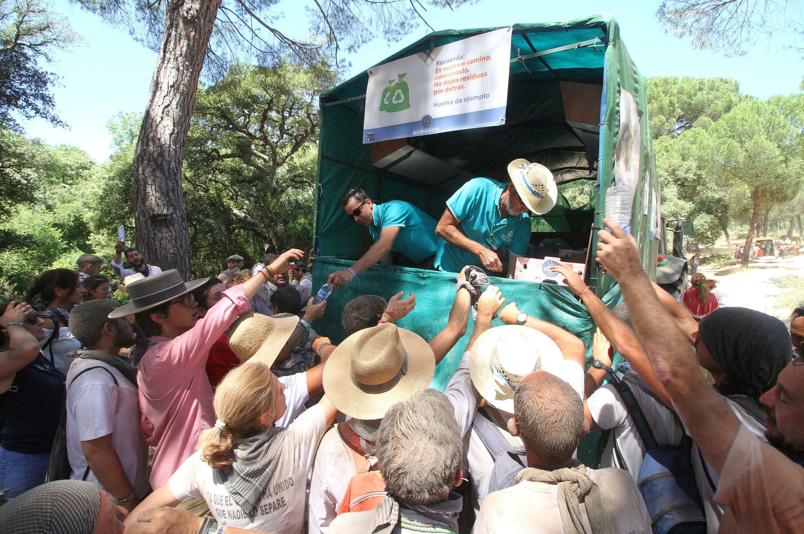 Peregrinos de la Hermandad de Huelva piden botellas de agua durante el camino, en una pasada romería.