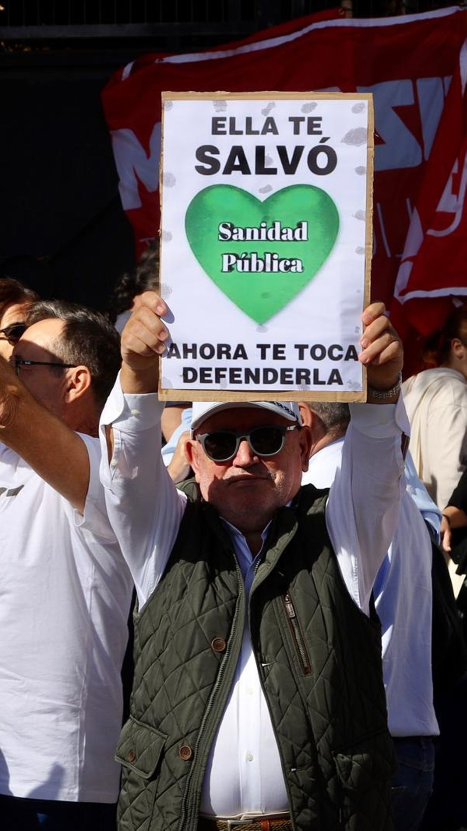 Un manifestante en la protesta sostiene un cartel en defensa de la sanidad pública.