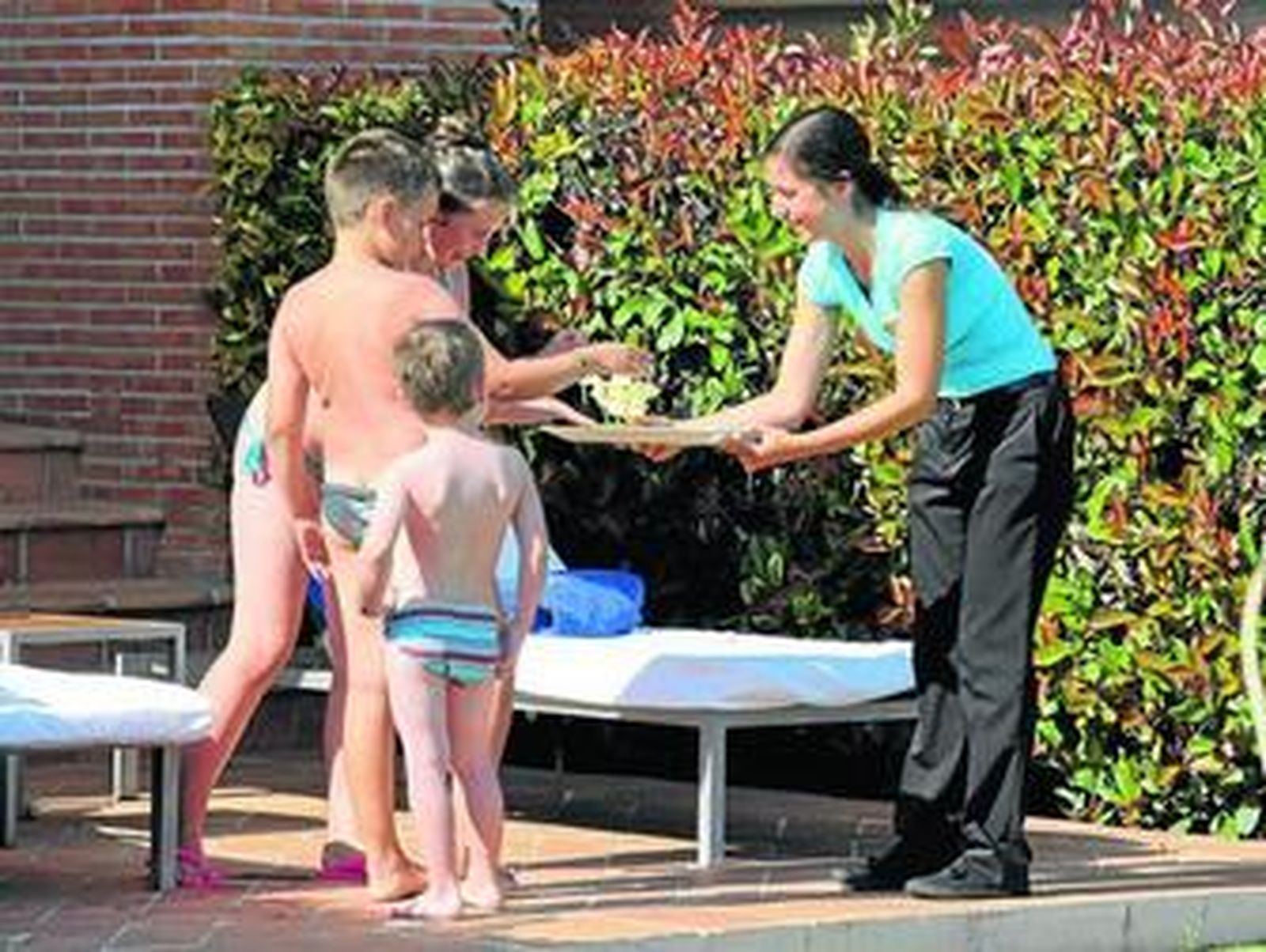 Una camarera atiende a unos niños en un hotel de la Costa del Sol.