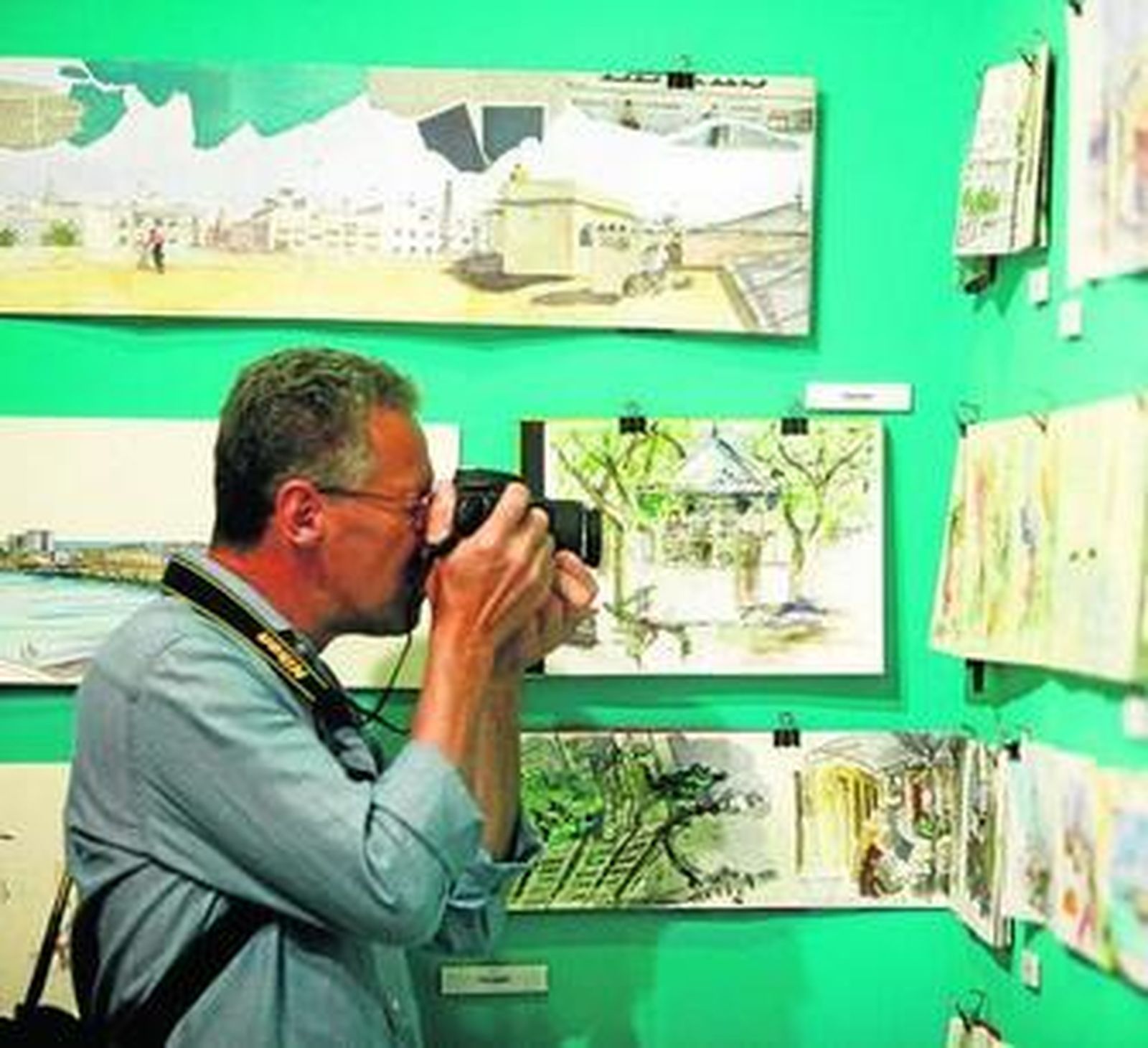 Un hombre realiza una fotografía a una de las ilustraciones de la exposición en la Casa de Iberoamérica.