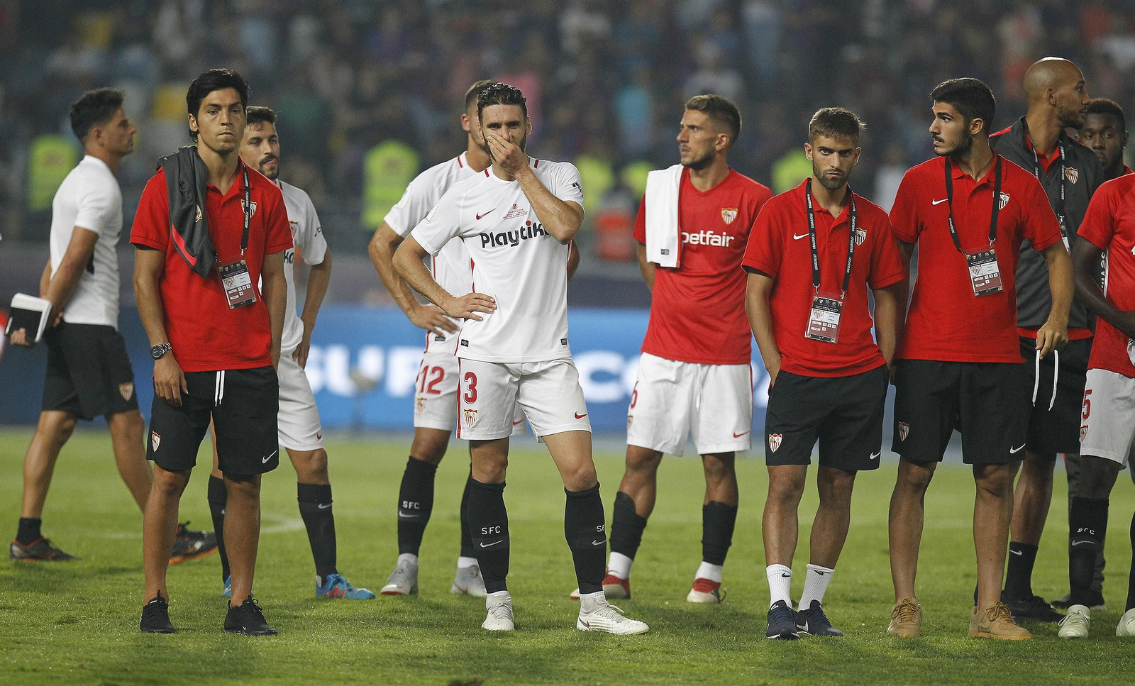Varios integrantes de la plantilla sevillista esperan en el césped la entrega de trofeos.