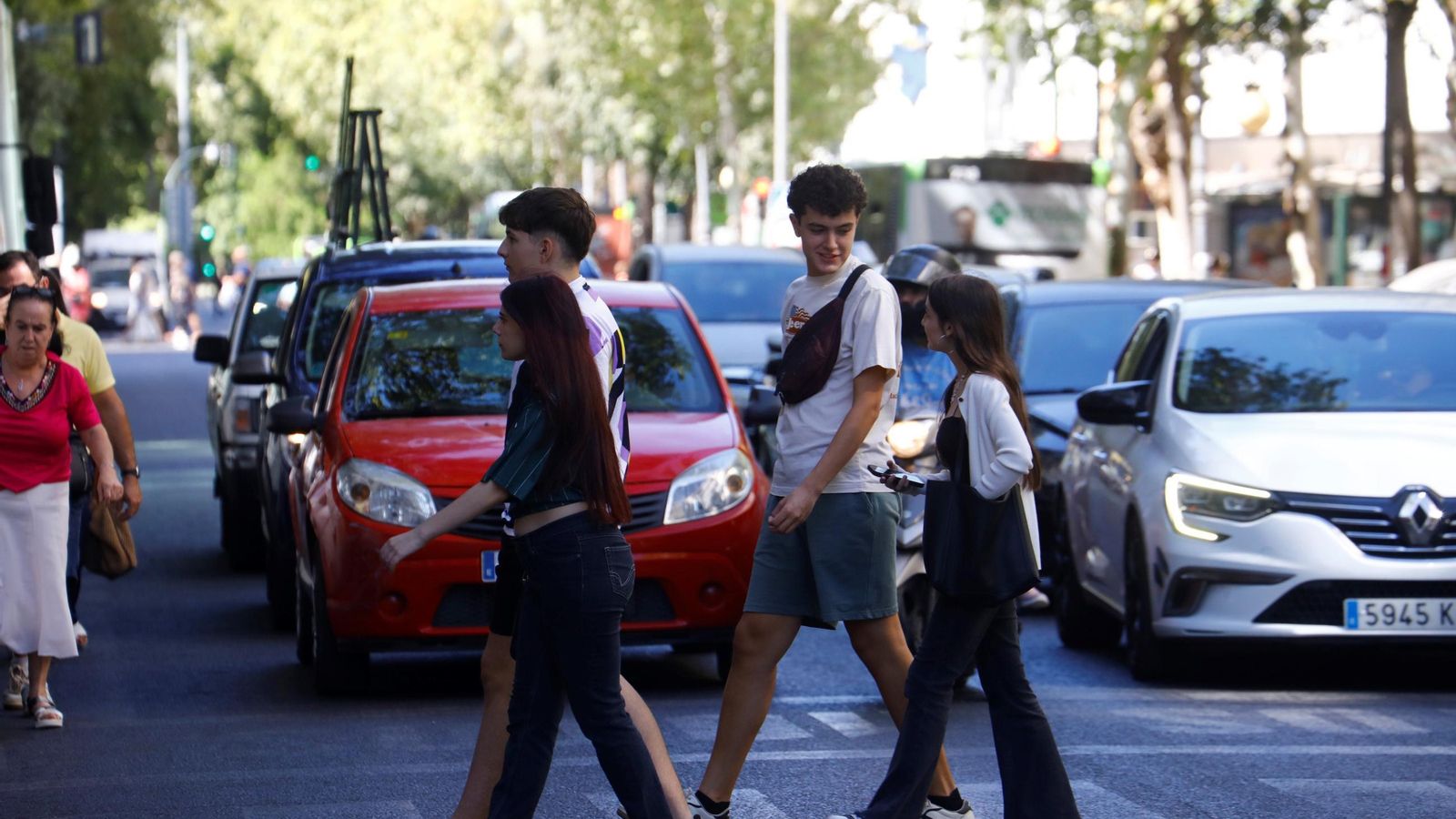 Unos jóvenes cruzan por un semáforo.