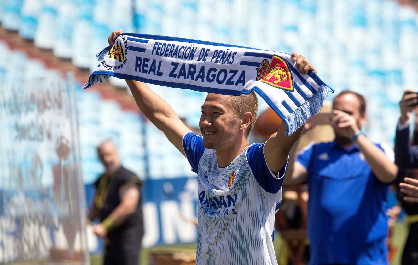 Kagawa saluda a los aficionados con una bufanda del Zaragoza durante su presentación.