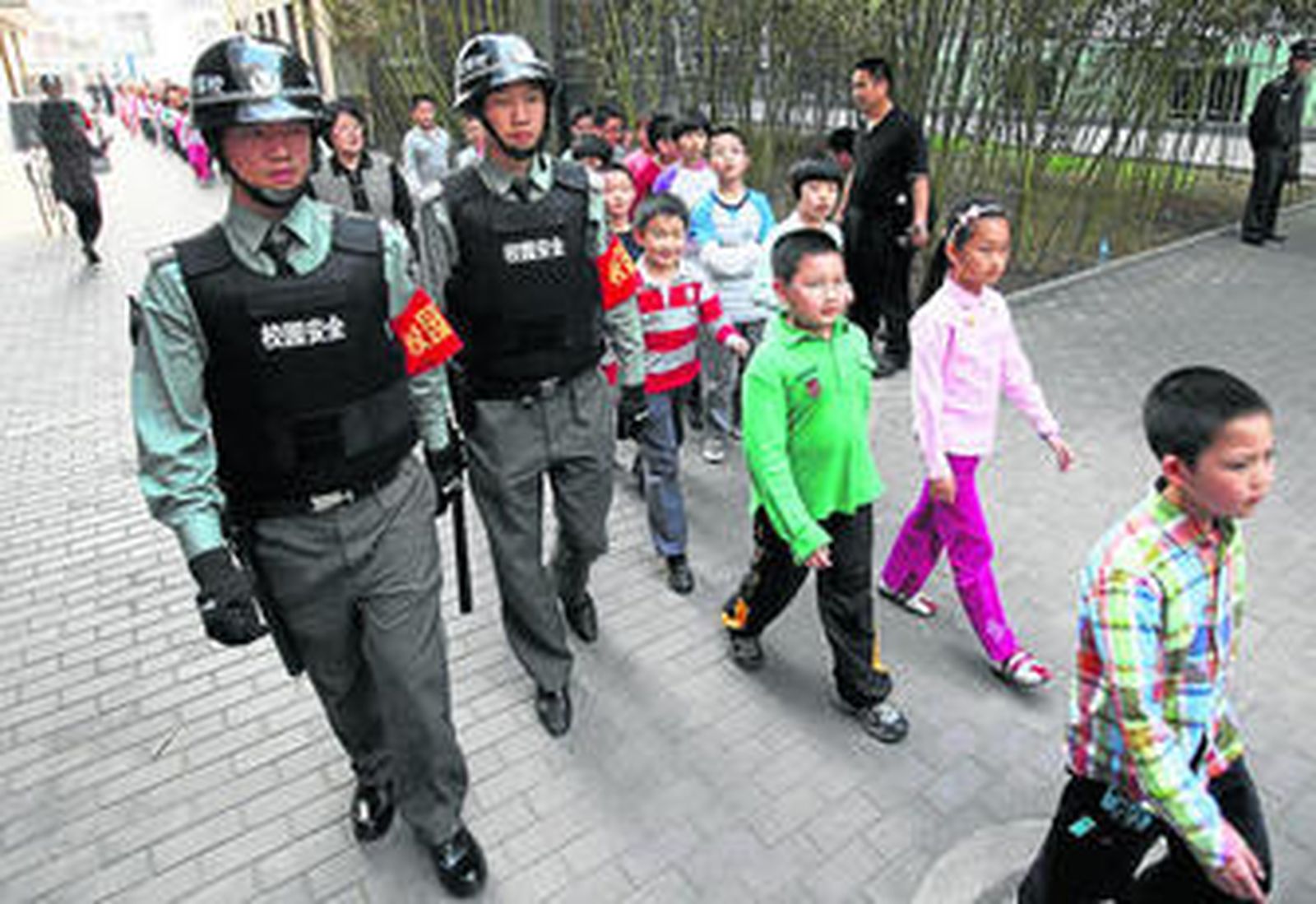 Niños chinos acuden al colegio protegidos por policías para evitar atentados o secuestros.