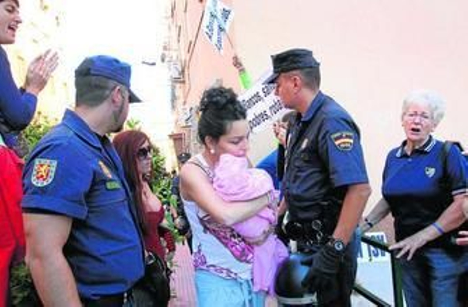 Mayte con su bebé abandona su casa en Las Flores desahuciada por impago. Alrededor, vecinos y miembros del 15-M.