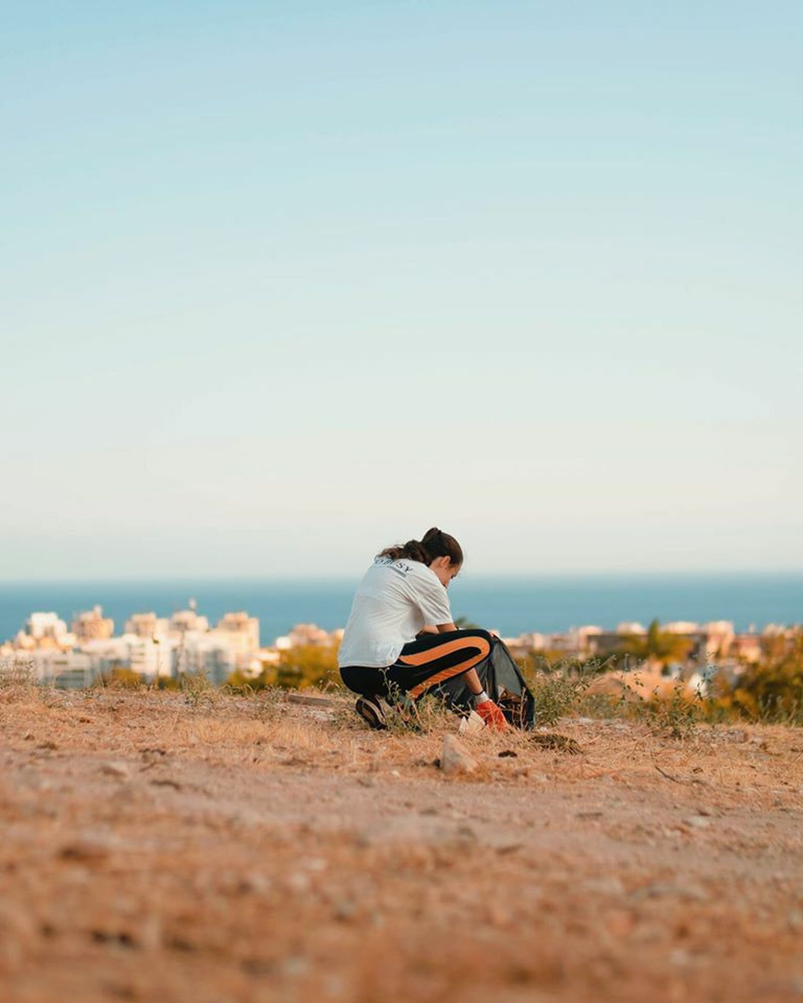 Una joven recoge basura en una zona de campo en Marbella.
