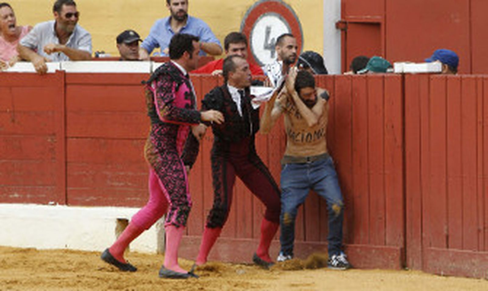Dos miembros de la cuadrilla de Morante de la Puebla reducen a un manifestante antitaurino. / EFE