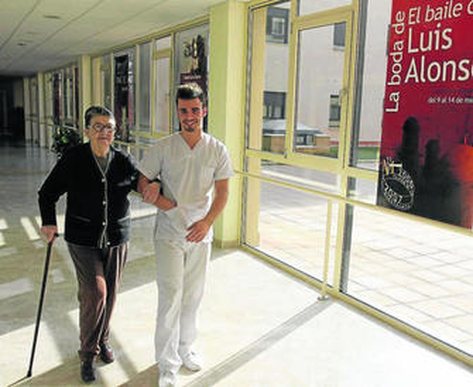 Una persona mayor pasea por el centro con uno de los enfermeros.