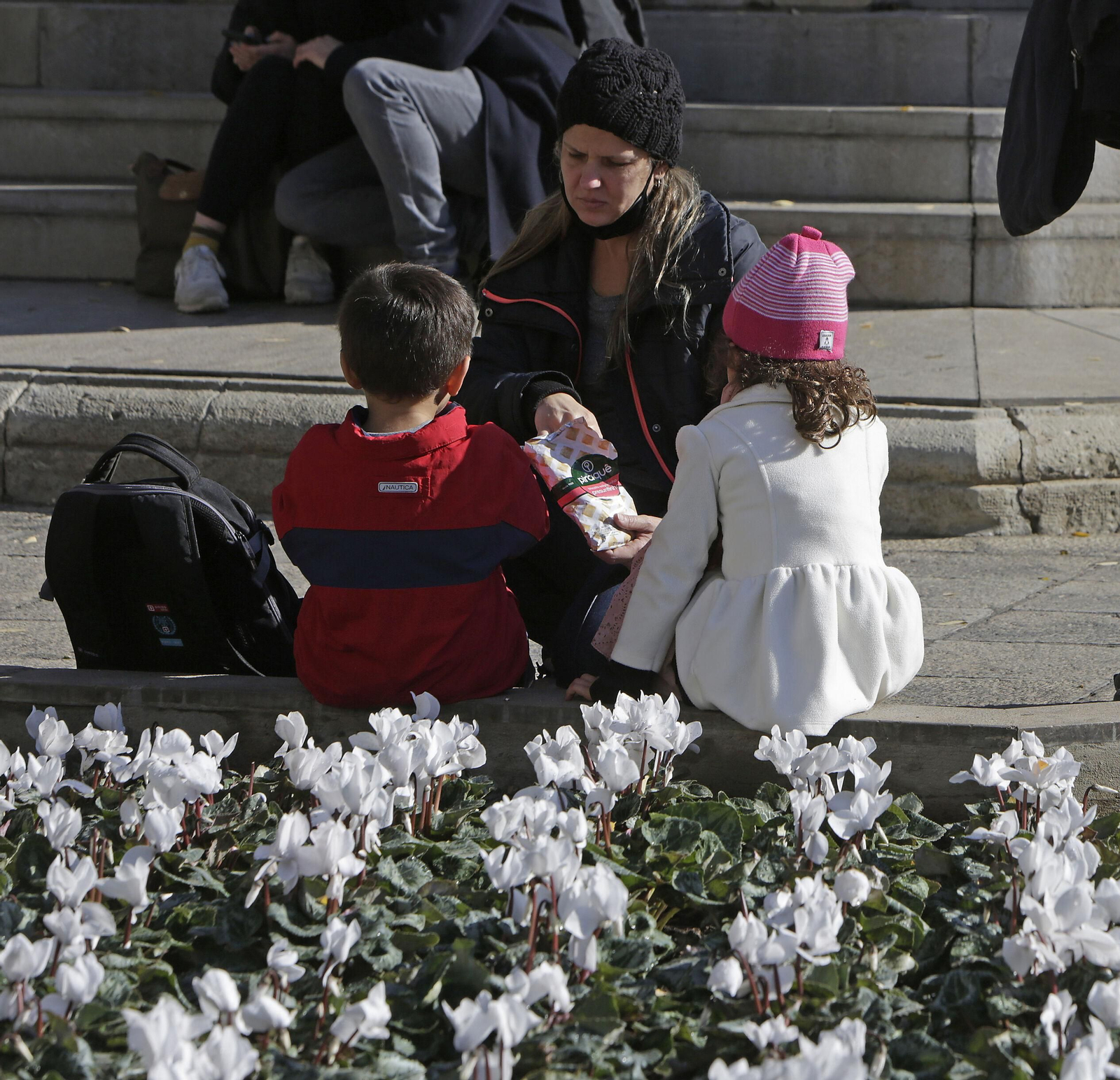 Una mujer junto a dos menores en una céntrica plaza de Sevilla.
