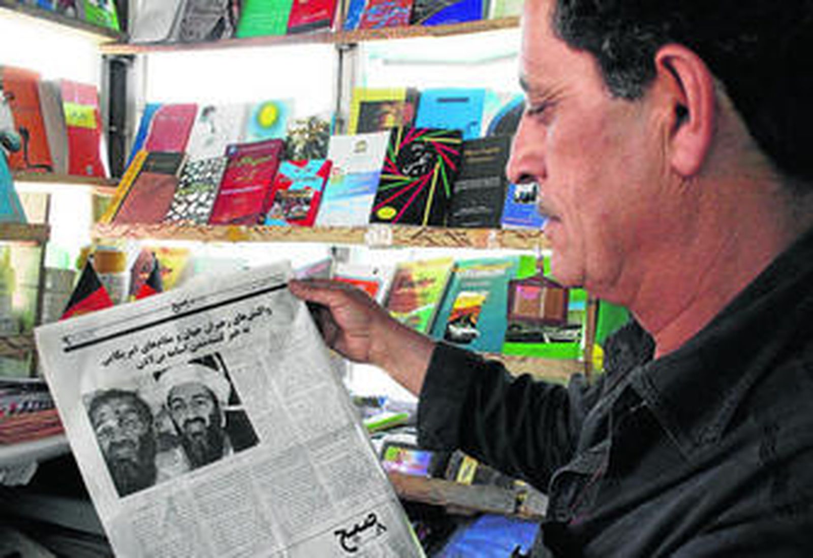 Un librero afgano lee en el periódico la noticia de la muerte de Ben Laden ilustrada con una fotografía falsa del cadáver.