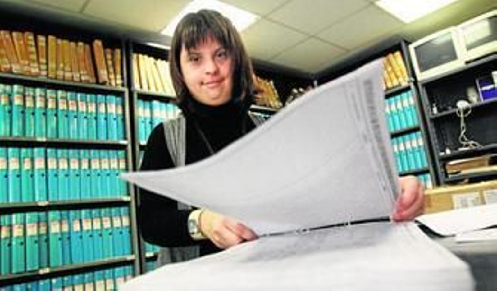 Arriba, una chica con síndrome de Down trabaja en un registro de la propiedad y en la imagen  de abajo, un hombre discapacitado lo hace como reponedor en una gran superficie.