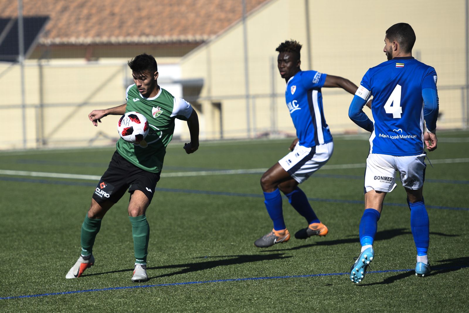 Un jugador del Huétor Vega controla el balón con el pecho ante la mirada de dos rivales.
