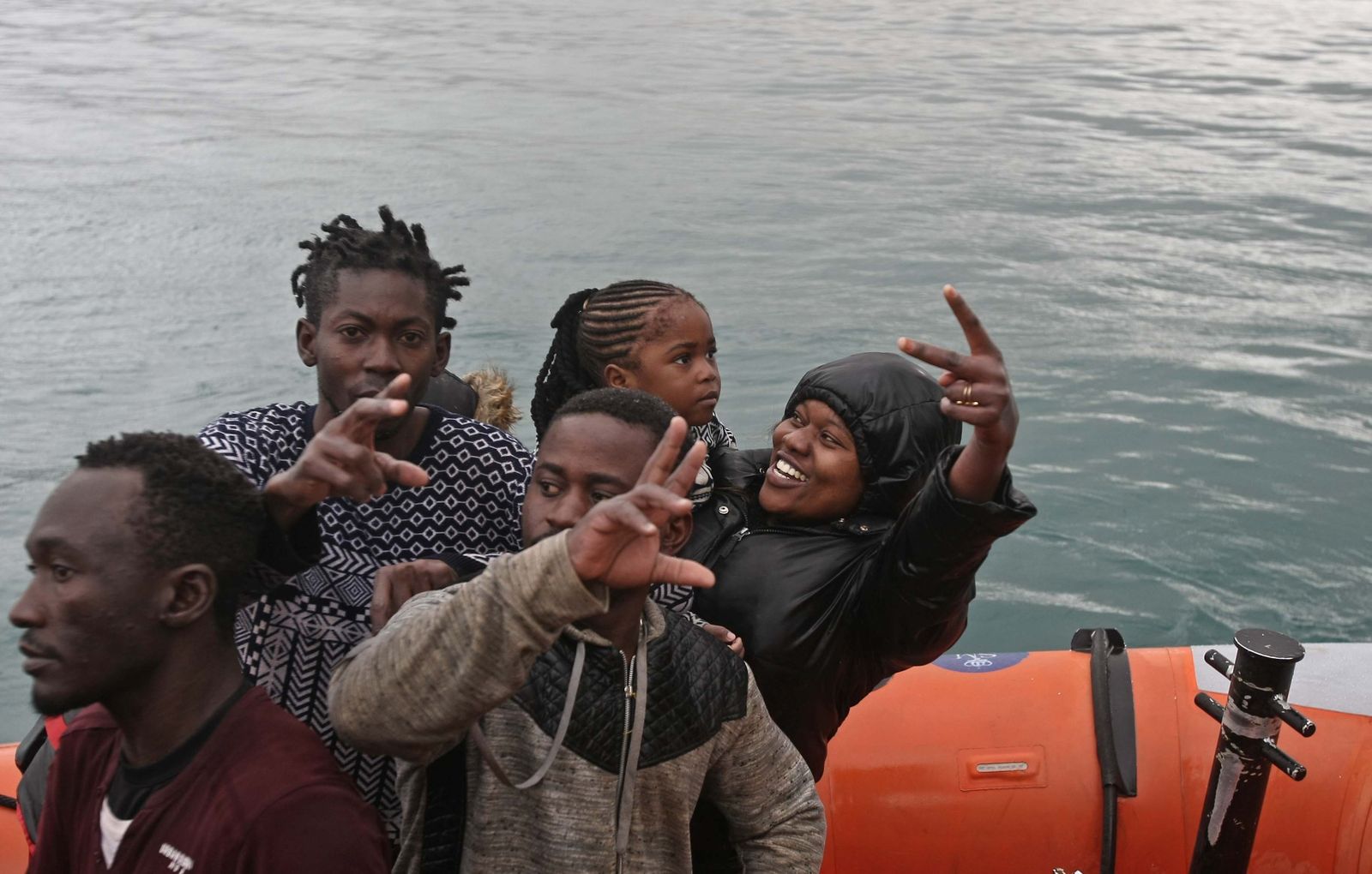 Migrantes mirando a las cámaras a su llegada a las costas de Tarifa con expresión de felicidad.