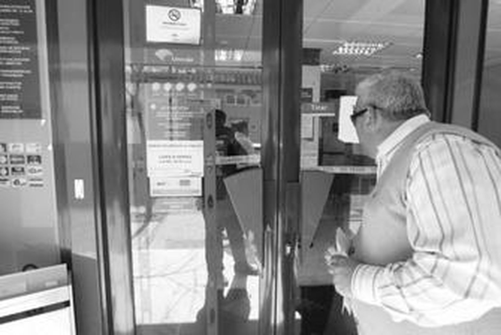 Un hombre mira el interior de la sucursal de Unicaja de Palmones, precintada por la Guardia Civil.