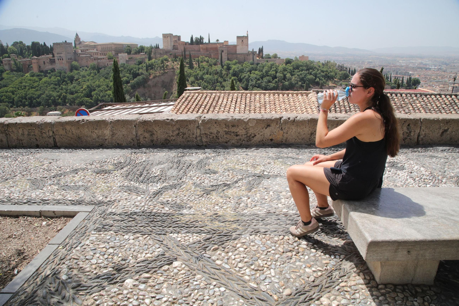 Una chica se refresca frente a la Alhambra de Granada Una chica se refresca frente a la Alhambra de Granada