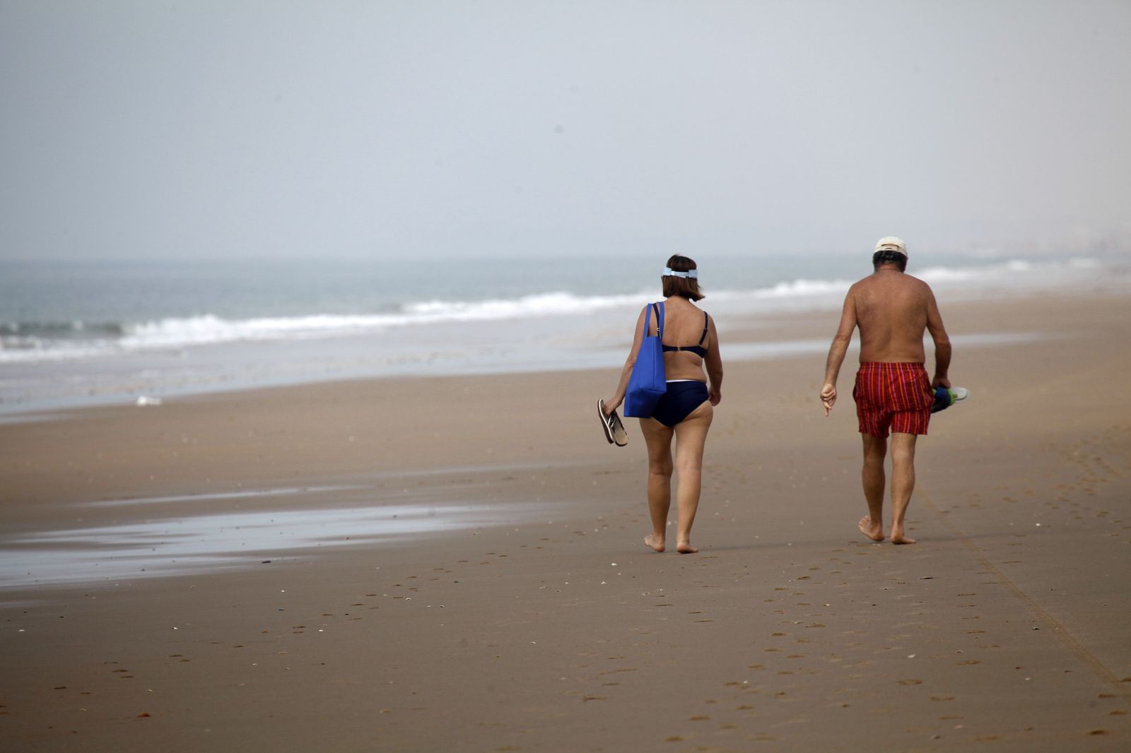 Una pareja pasea junto a la orilla de la playa en una cálida tarde veraniega.