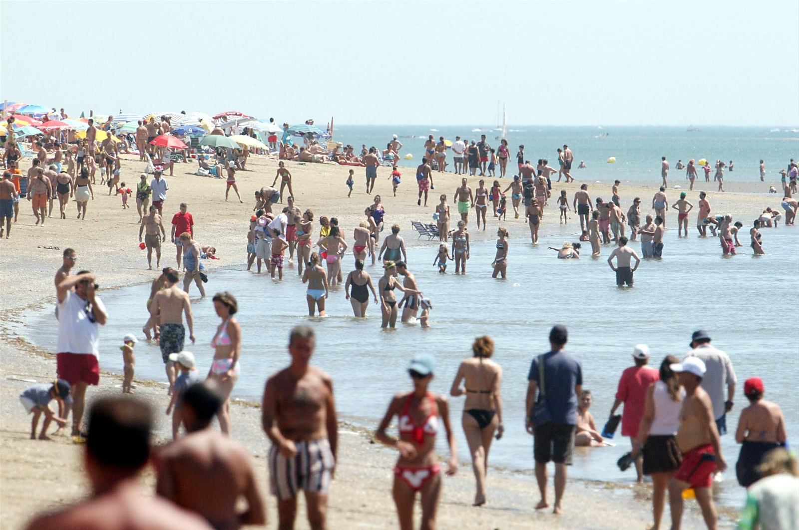 Decenas de bañistas paseando por la orilla de la playa de isla Canela, en Ayamonte.