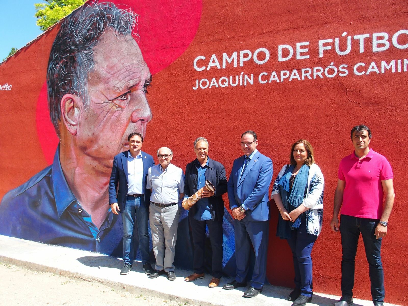 Joaquín Caparrós posa ante el mural del campo municipal de Cuenca entre las autoridades.