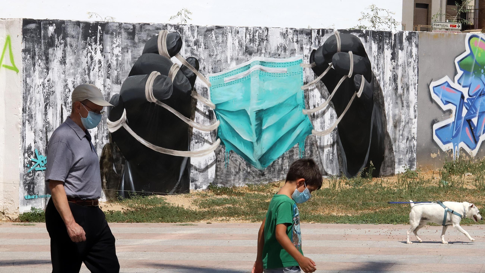 Una persona mayor pasea junto a un pequeño por la calle.