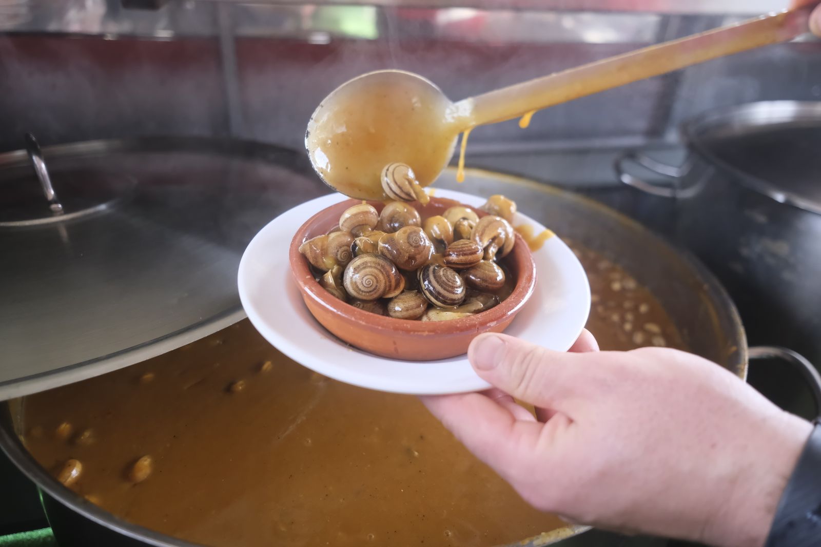 Un trabajador de un puesto sirve una ración de caracoles.