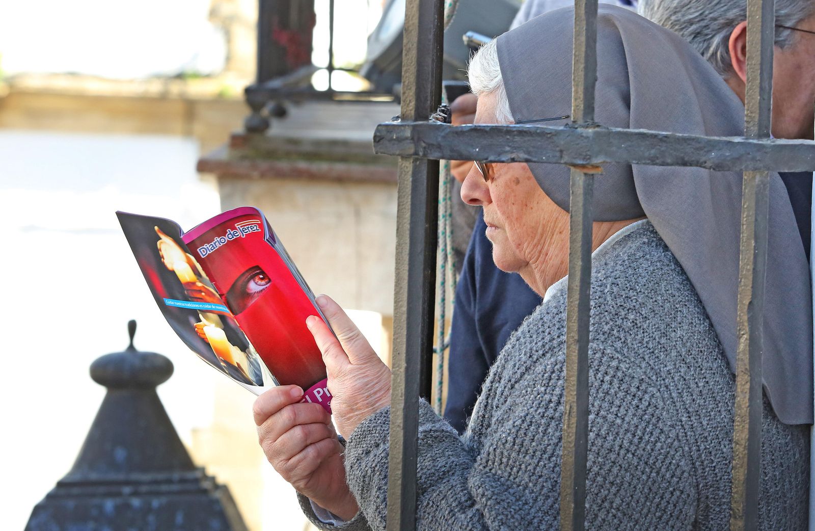 Una religiosa ojea la guía de Diario de Jerez mientras esperaba la salida de las Tres Caídas en un balcón de San Lucas.