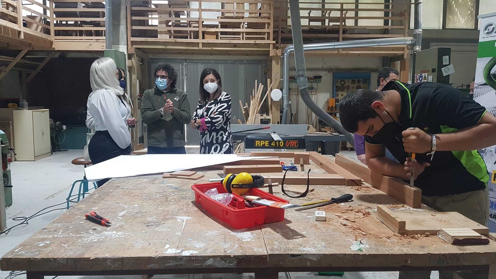 Uno de los alumnos trabaja mientras los visitantes observan su trabajo.