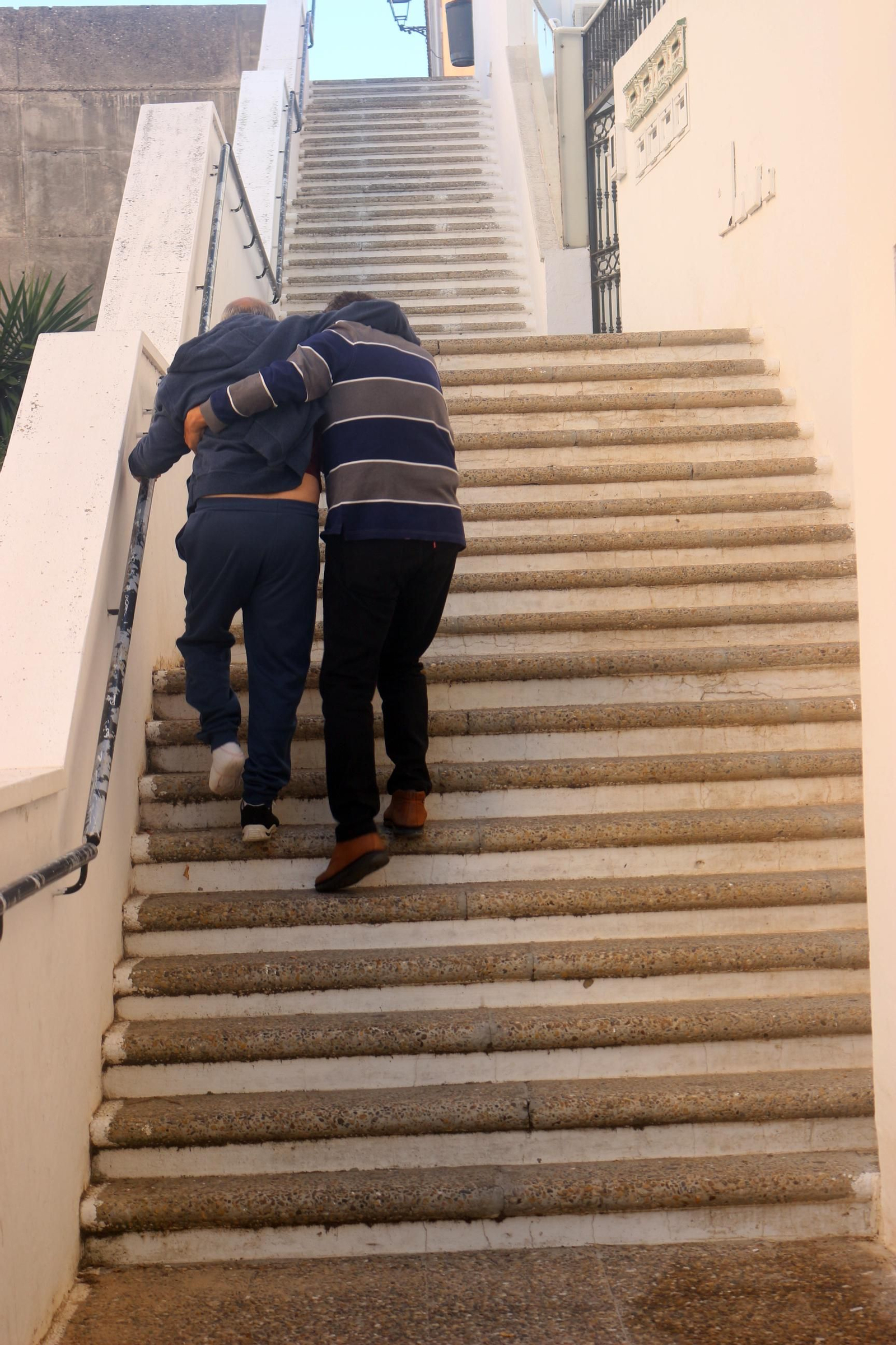 Manuel ayuda a su hermano Paco a subir la escalera que le lleva a su casa