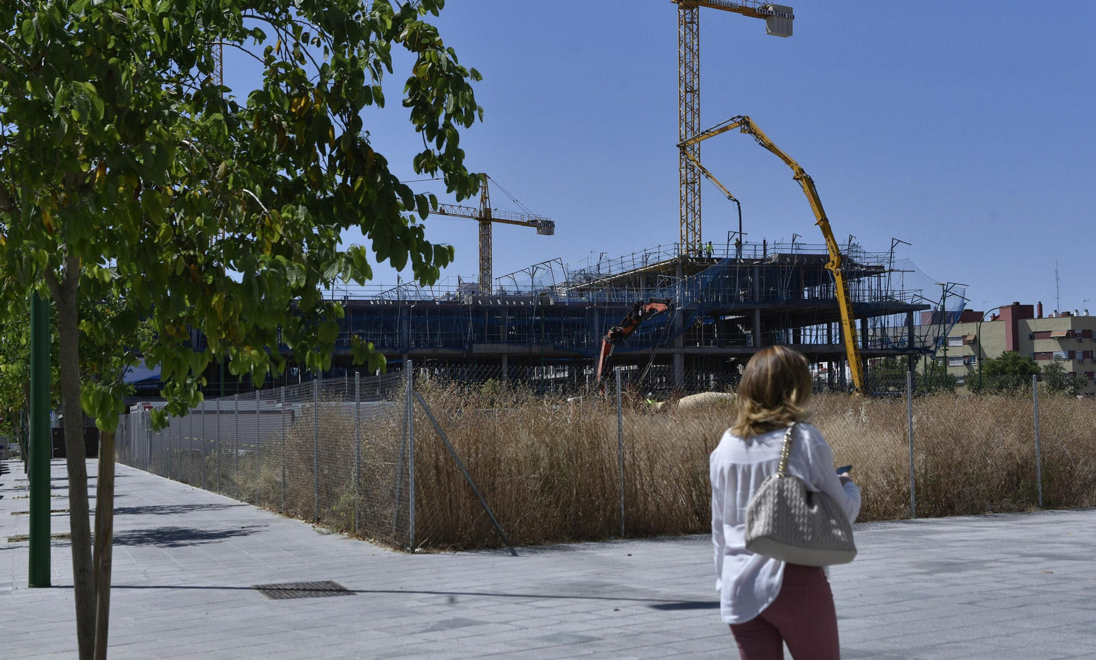 Una mujer pasea junto a una parcela destinada a vivienda protegida en Sevilla