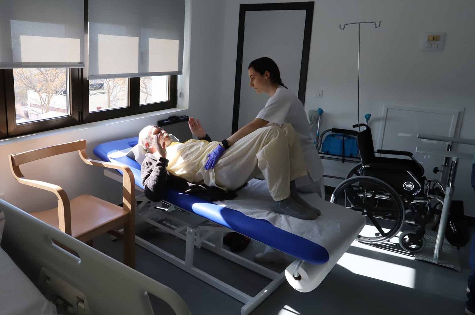 Una fisioterapeuta atiende a un paciente.