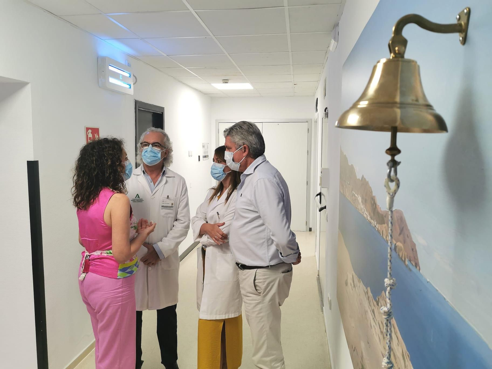 El delegado territorial de Salud, el director gerente del hospital y la presidenta de la AECC en Almería junto a la campana.