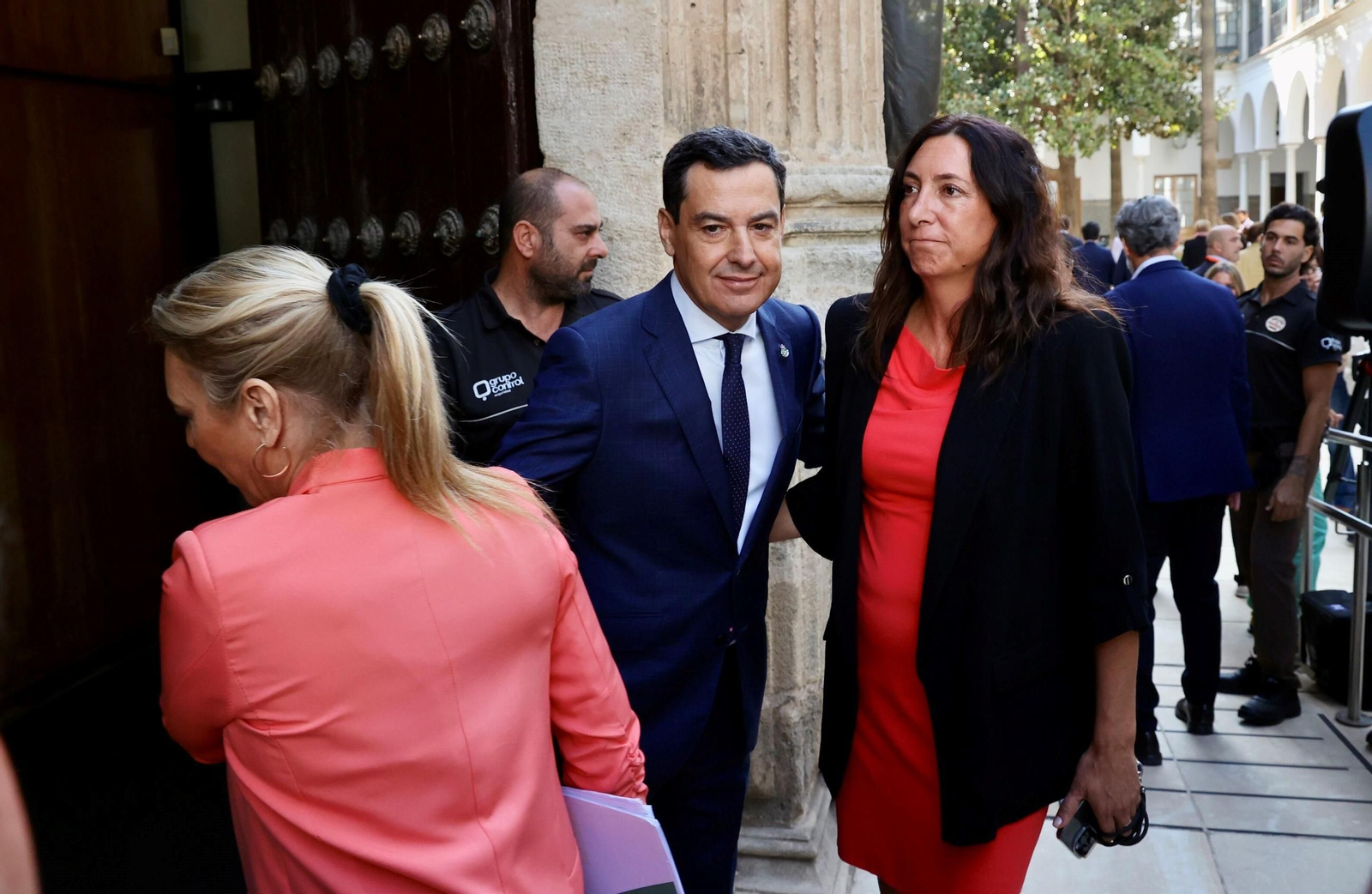 Juanma Moreno entrando en el salón de plenos del Parlamento junto a Carolina España y Loles López.