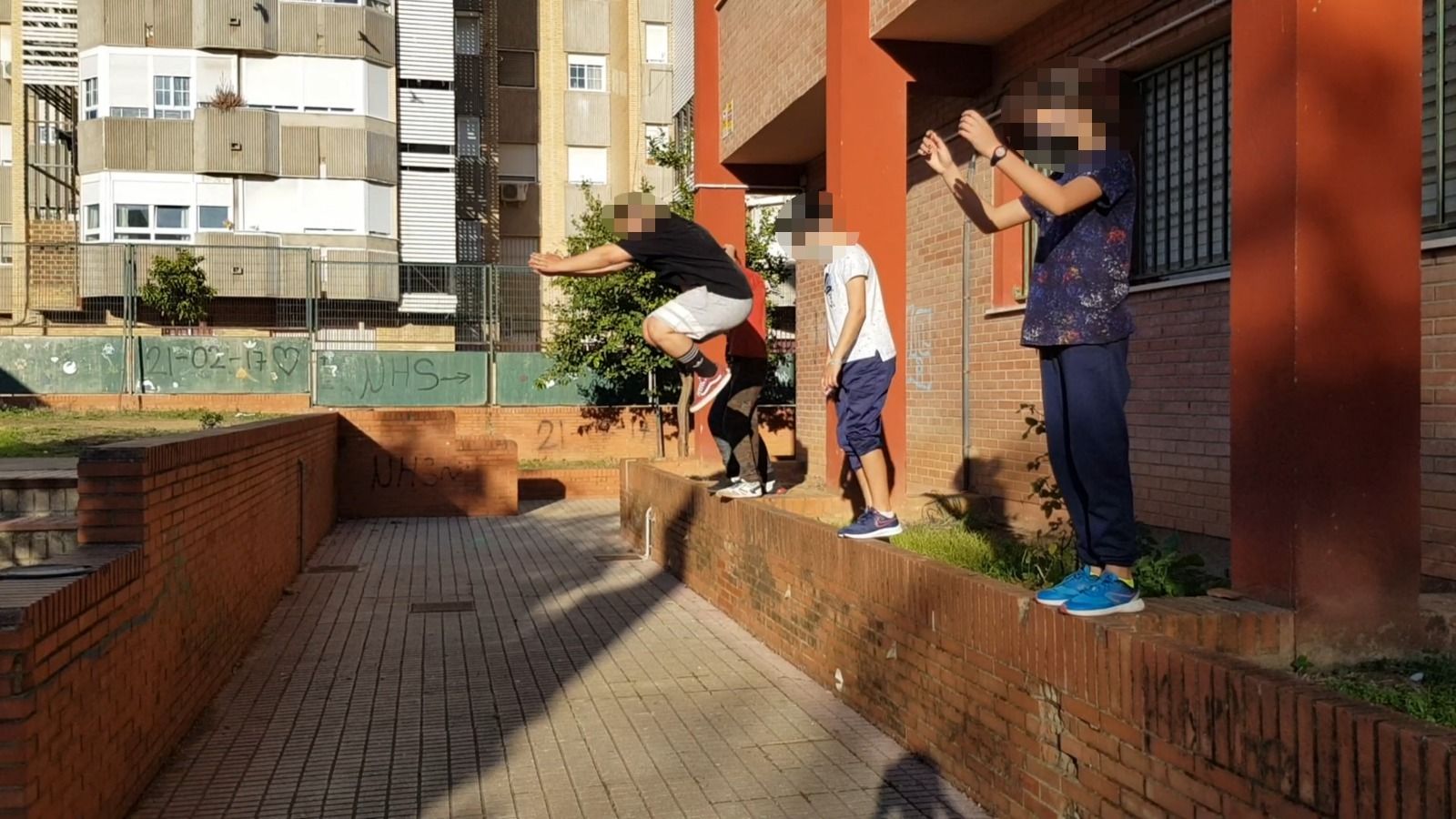 Varios chicos practicando 'parkour' en el patio de su centro educativo.