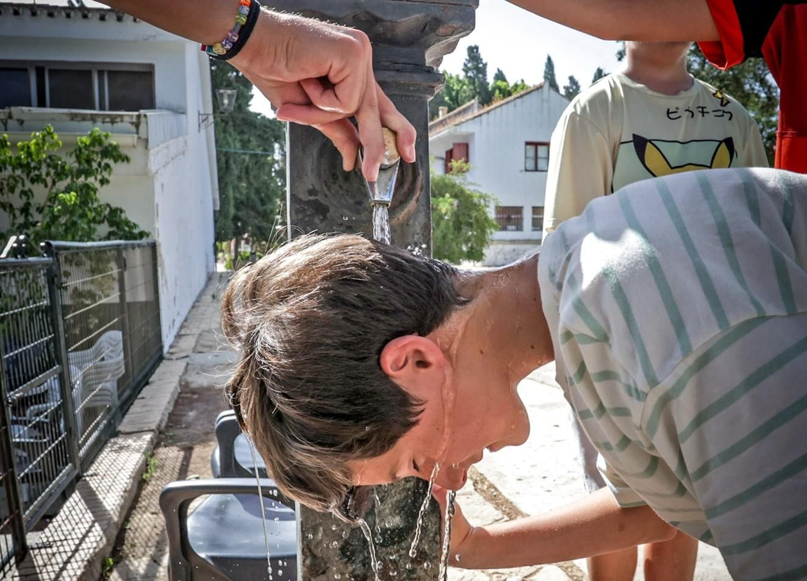 Unos adolescentes se refrescan con agua en una fuente en Jerez