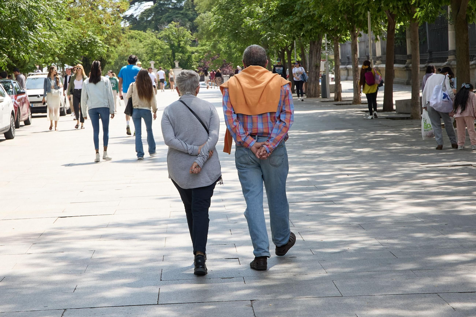 Dos personas mayores pasean por la calle.