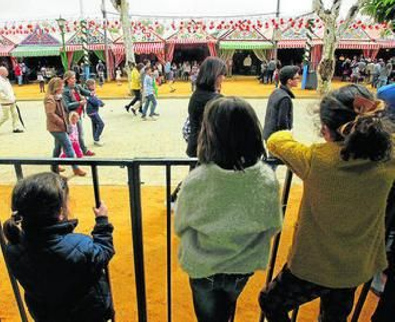 Varios niños observan el ambiente de la pasada Feria desde el interior de una caseta.