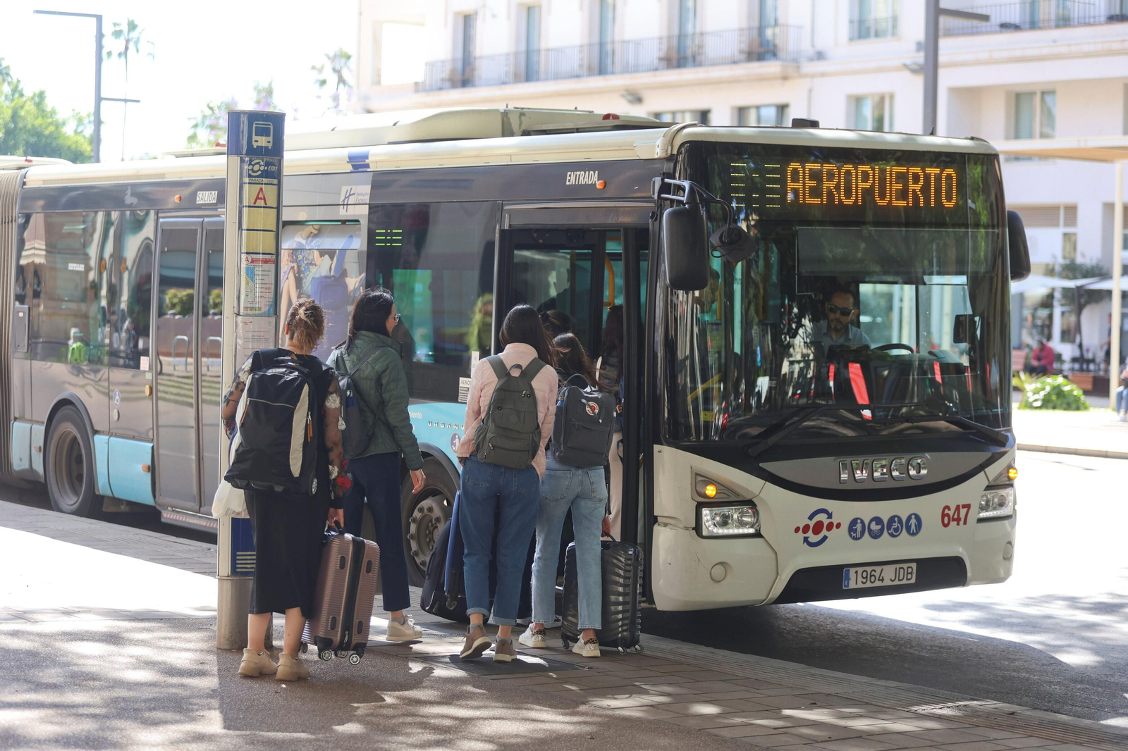 Turistas con maletas en la parada de autobús de la Alameda subiendo al autobús de la EMT dirección aeropuerto.