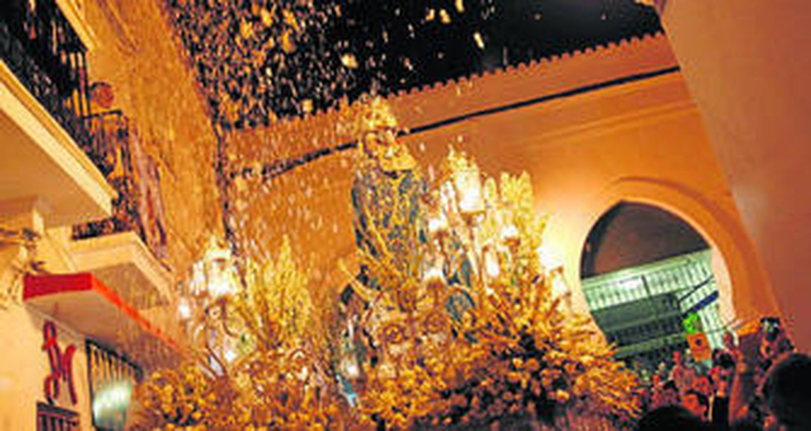 La patrona recibe una lluvia de pétalos a su paso por una de las calles del recorrido.