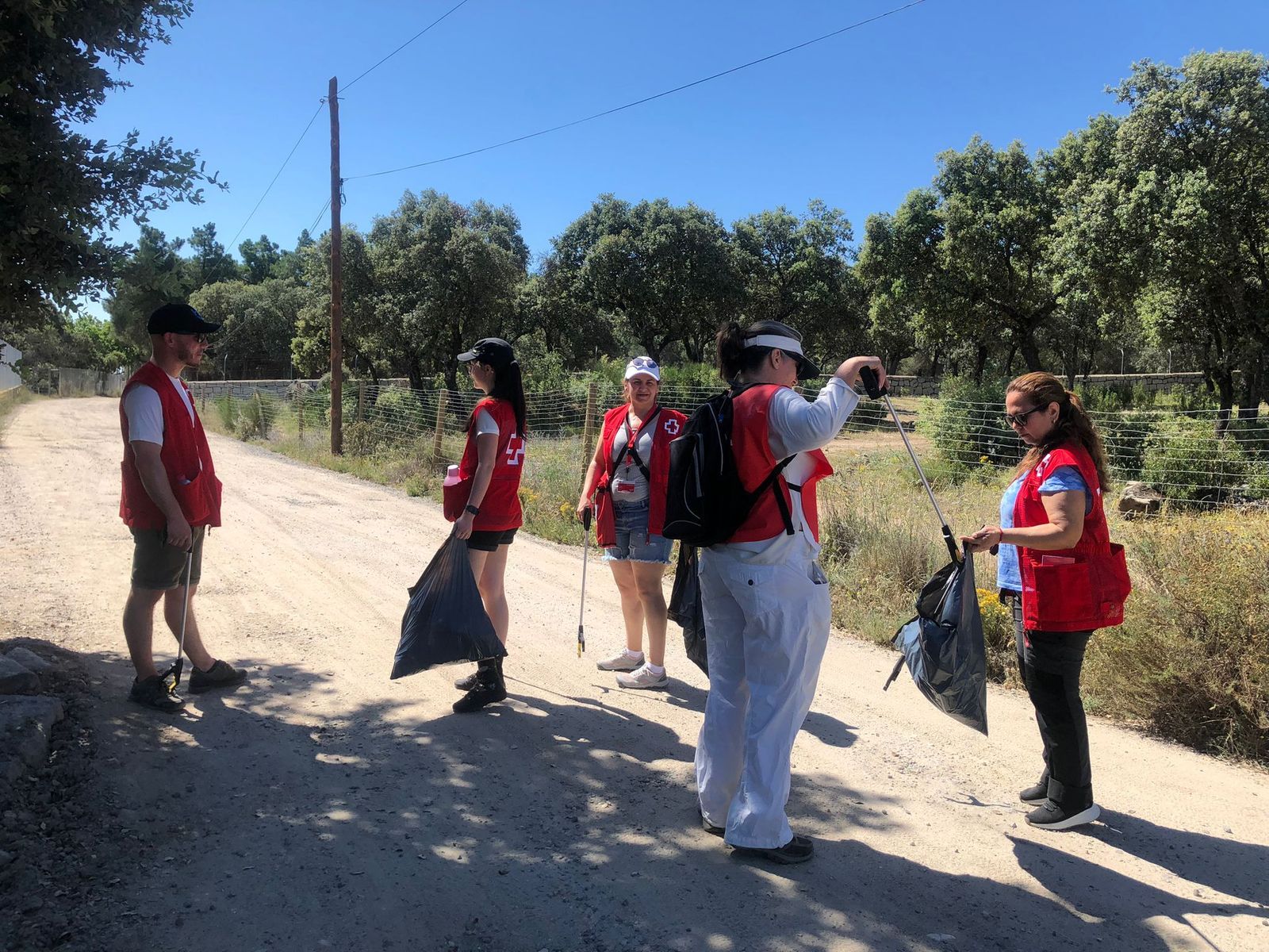 Voluntarios de Cruz Roja limpian una zona verde.