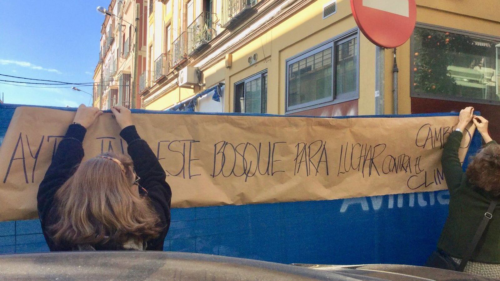 Dos mujeres colocan una pancarta crítica con la medida autorizada por el Ayuntamiento.