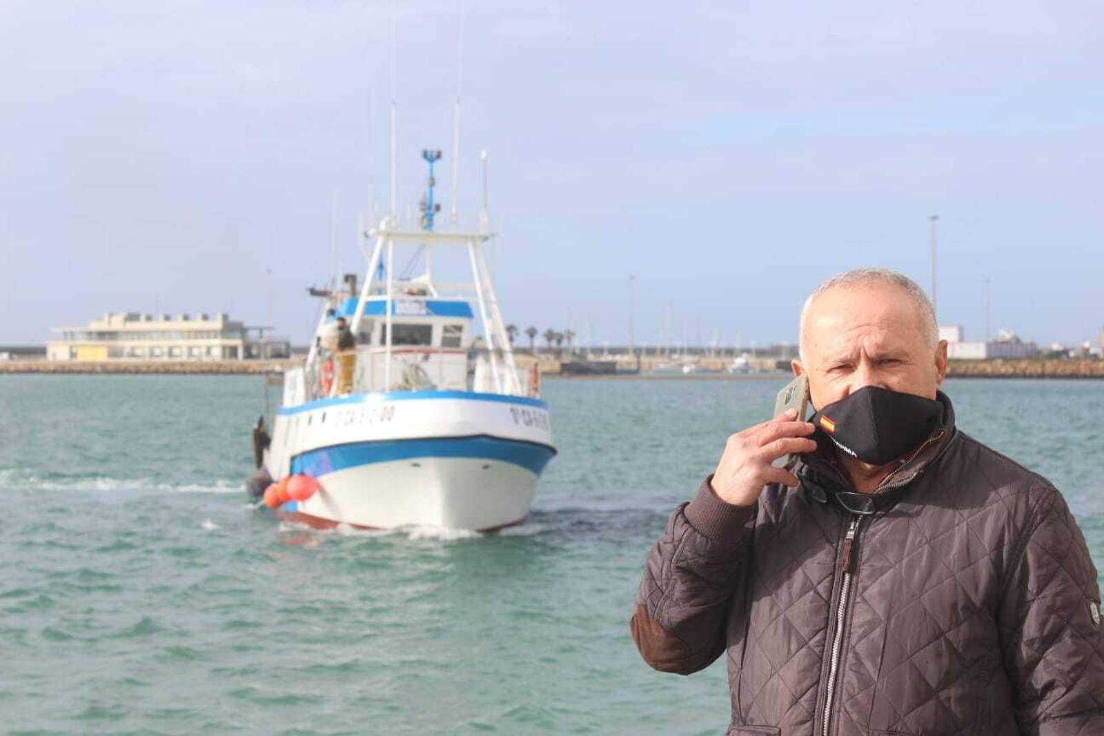 Andrés Barrera conversa por teléfono desde el muelle de Barbate con un pesquero llegando a puerto detrás suya. Andrés Barrera conversa por teléfono desde el muelle de Barbate con un pesquero llegando a puerto detrás suya.