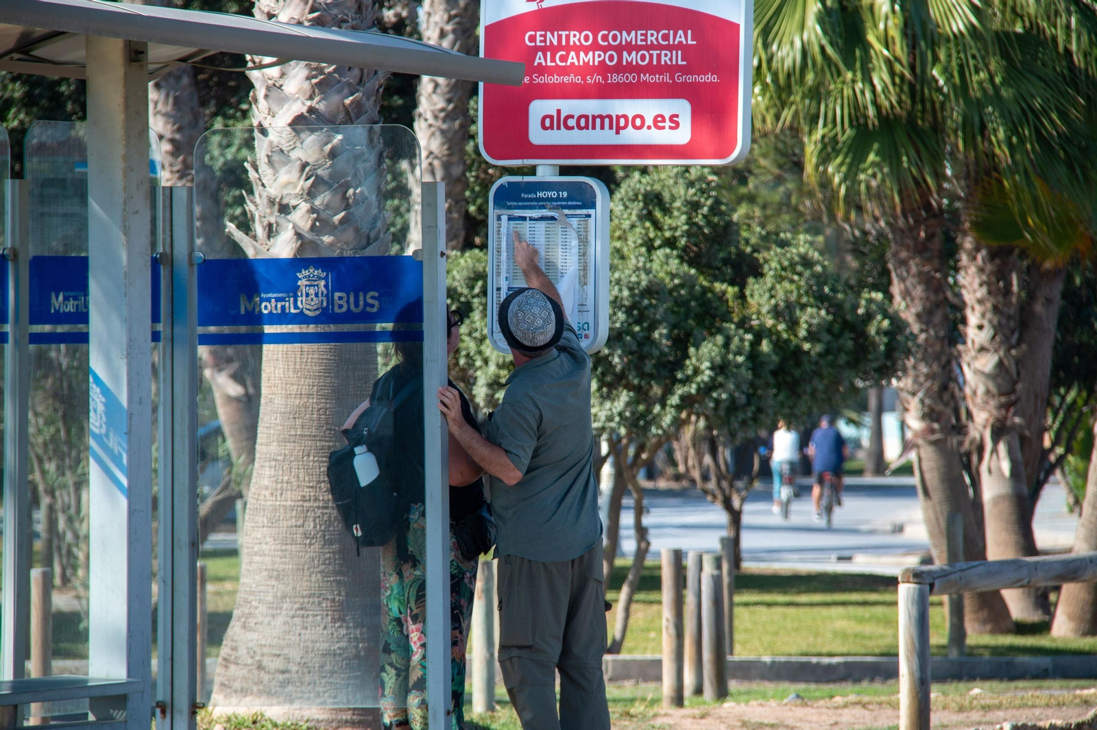 Dos turistas miran los horarios del autobus en la playa de Motril