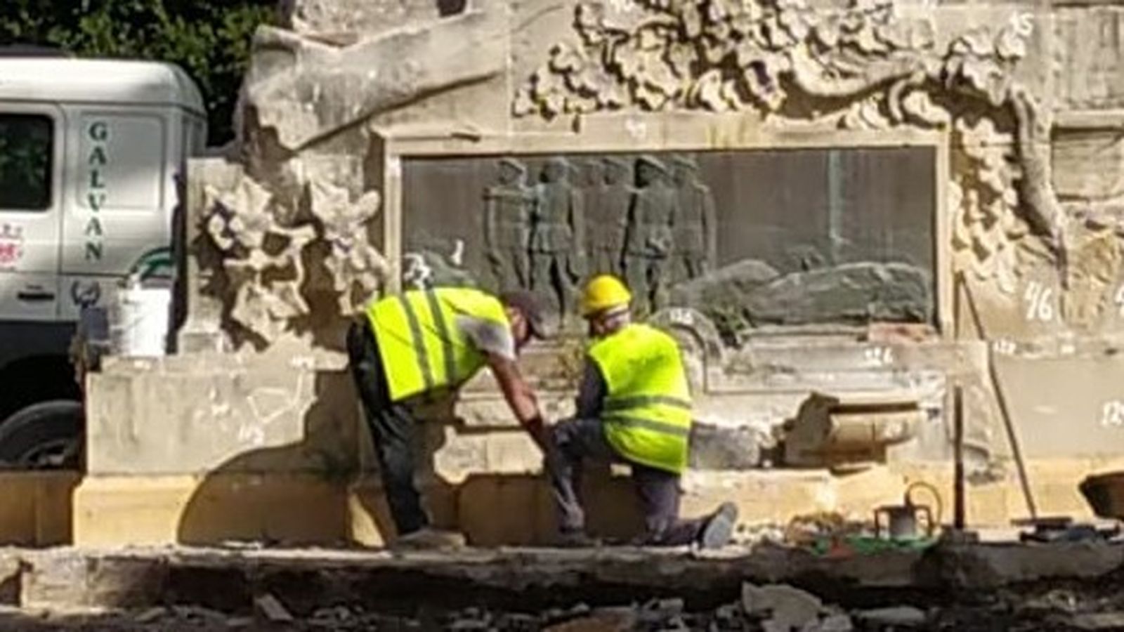 Operarios trabajando en el desmontaje de la fuente situada en la base del conjunto escultórico.