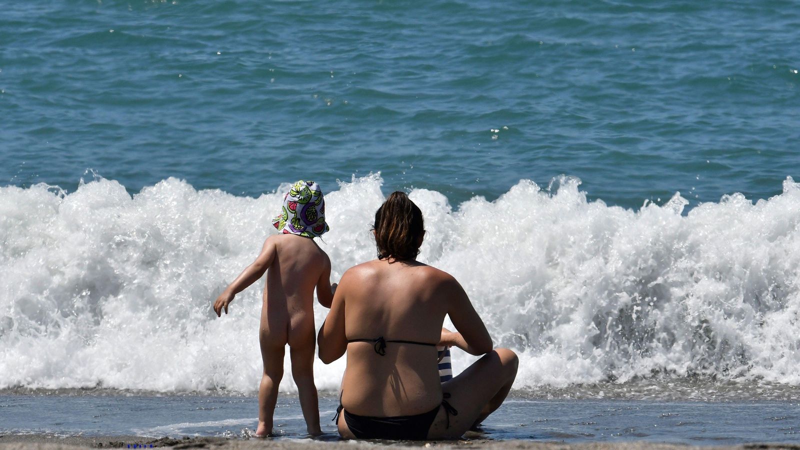 Un menor acompañado de un adulto en la orilla de la playa en Almería