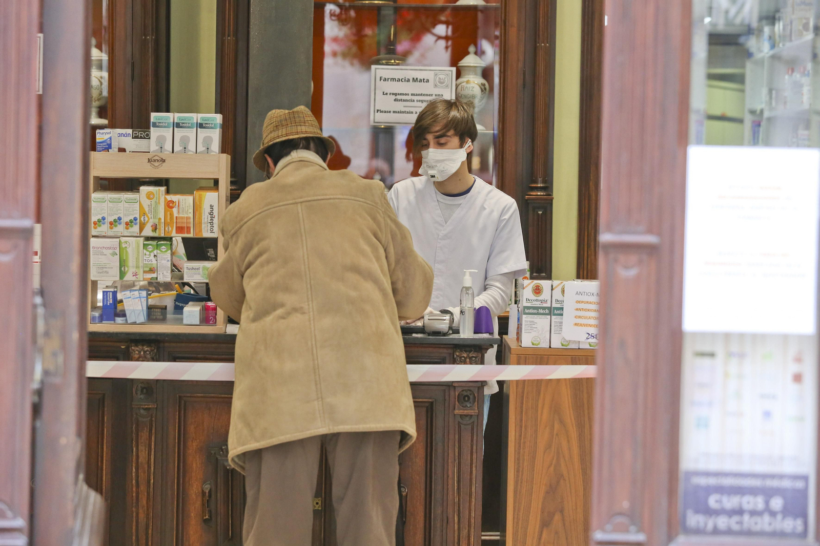 Un profesional de farmacia atiende a un paciente tras el mostrador.