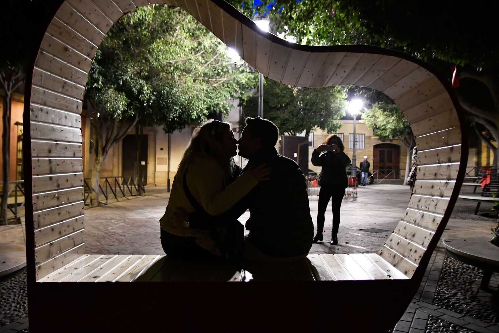 Un pareja  se fotografía en la plaza Campoamor de Almería, decorada para la celebración del Día de Los Enamorados.