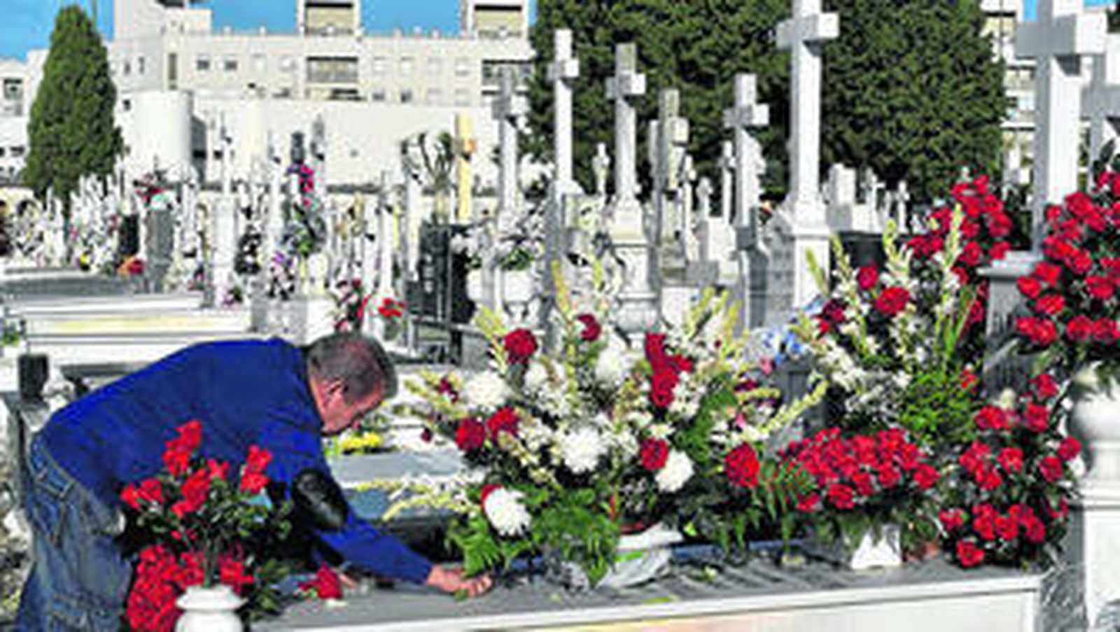 Un hombre coloca flores en una tumba, a primera hora de la mañana de ayer en el cementerio de Sevilla.
